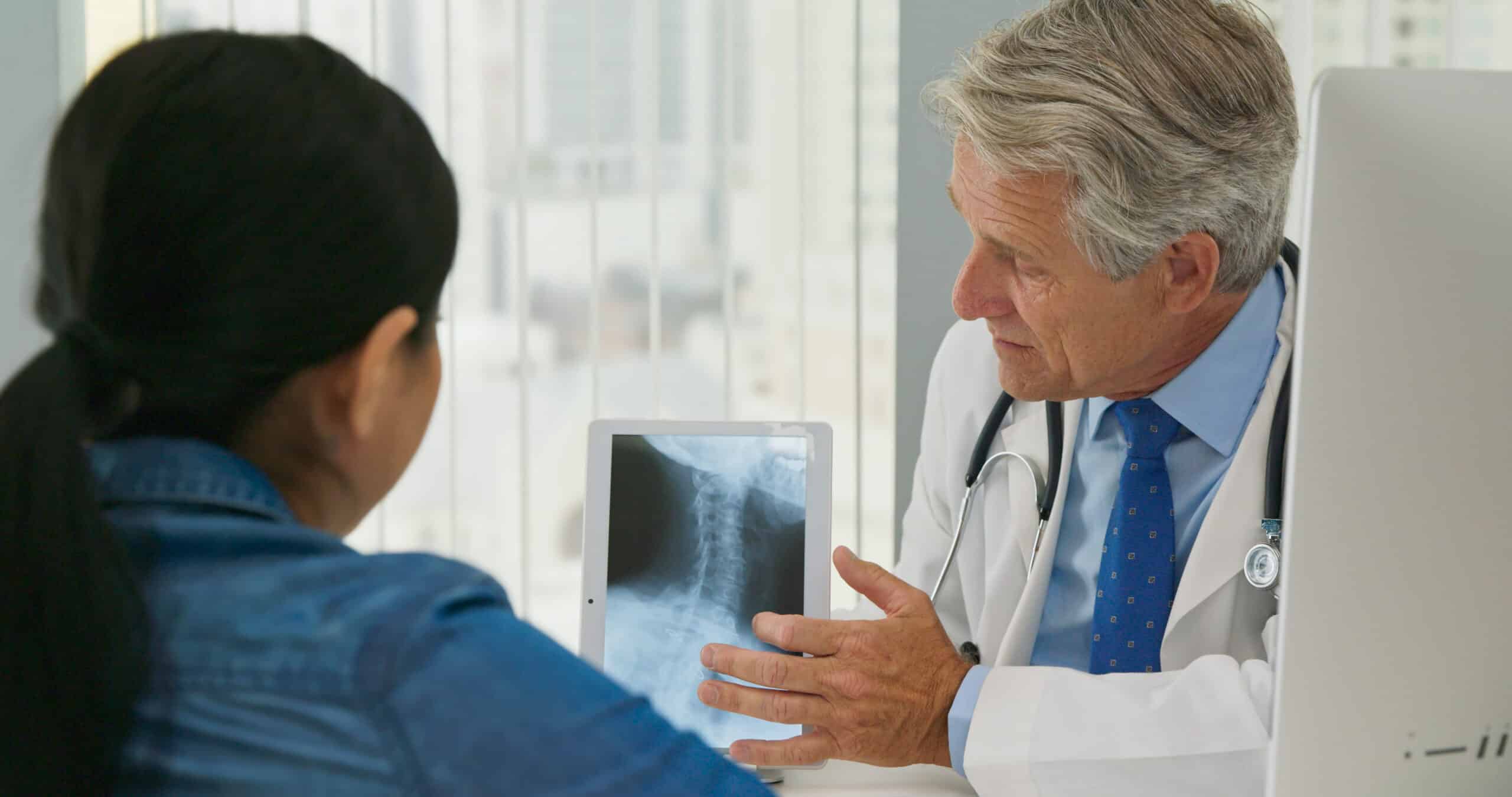 Woman Listening To Her Health Care Provider Explain Spinal Treatment With X Ray
